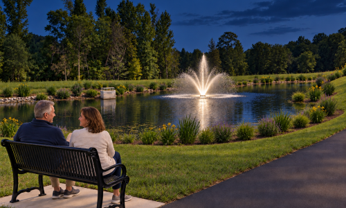 A man and a woman sitting on a bench in front of the fountain