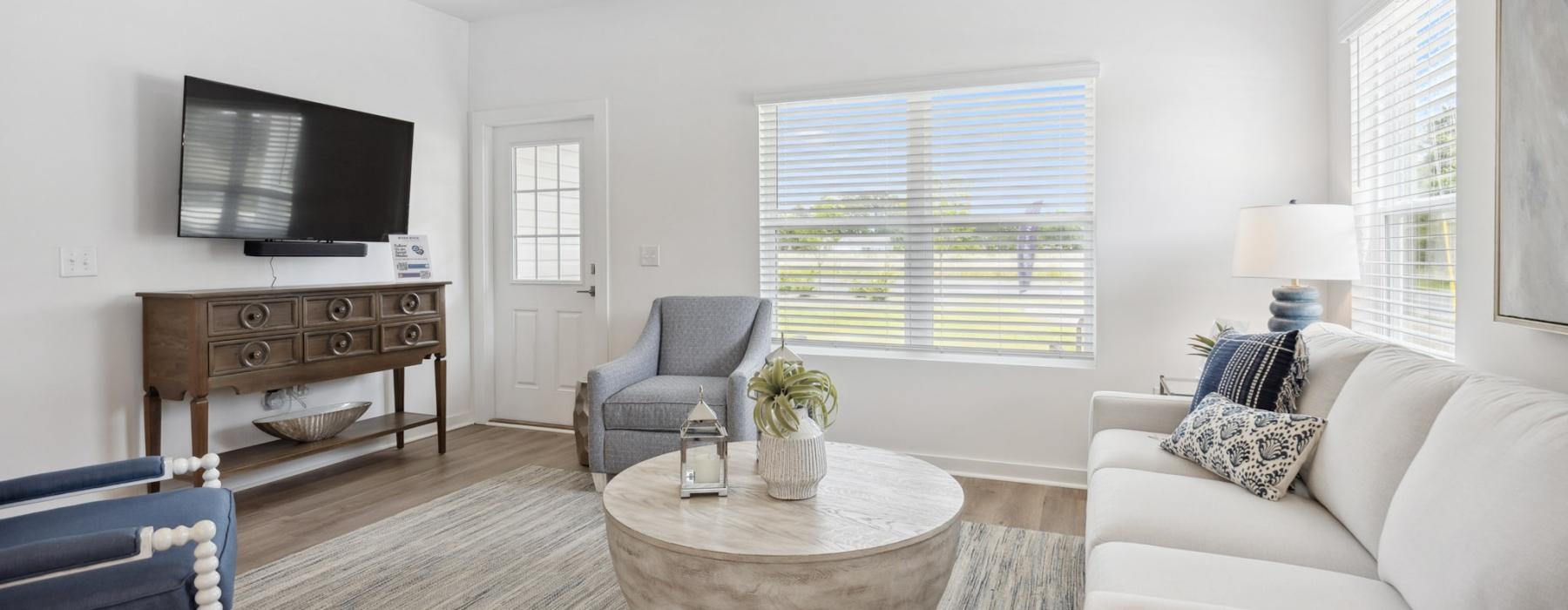 Model living room at our 55 and older rental homes in Dallas, NC, featuring wood grain flooring and a flat screen TV.