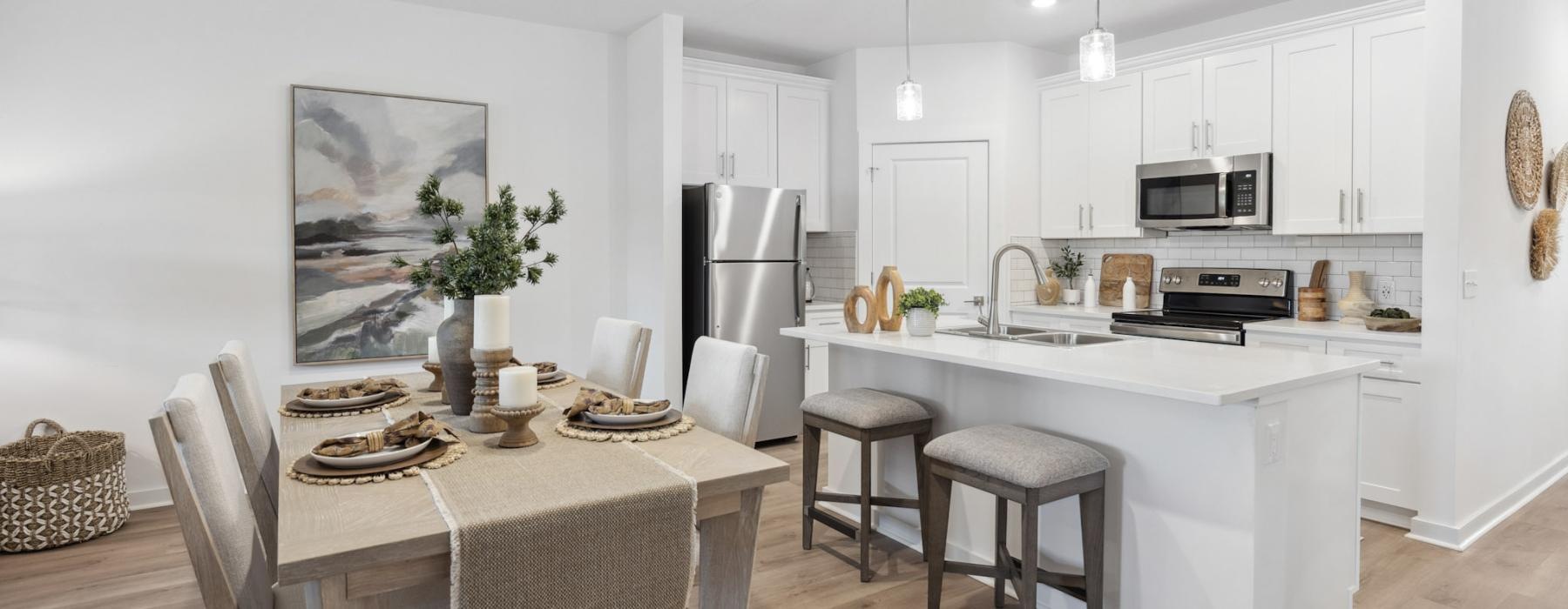 Model dining room at our 55 and older rental homes in Dallas, NC, featuring wood grain flooring and a view of the kitchen.