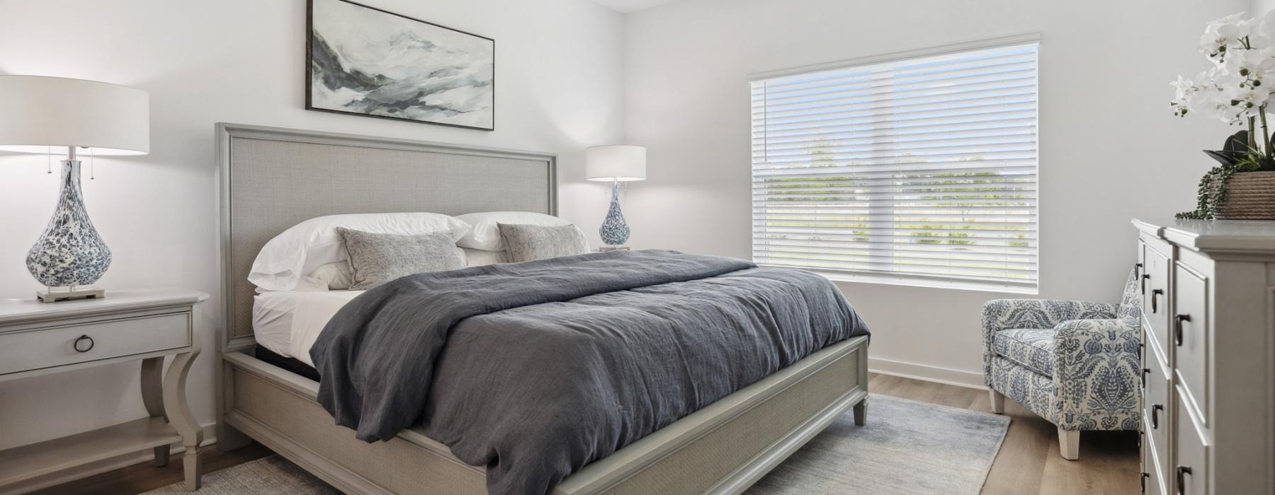 Model bedroom at our 55 and older rental homes in Dallas, NC, featuring wood grain flooring and windows with blinds.